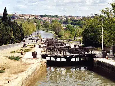 Écluses de Fonseranes : Patrimoine du Canal du Midi Écluses de Fonseranes sur le Canal du Midi à Béziers, escalier d'eau historique avec portes en bois et promeneurs.