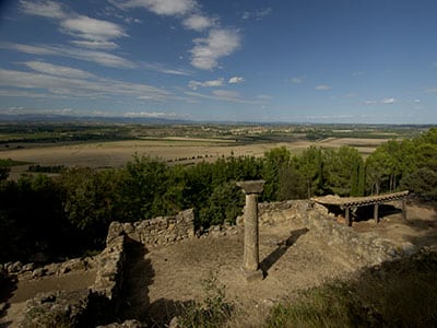 Vestiges Romains et Vue Panoramique sur la Vallée Colonne solitaire dans des ruines antiques surplombant une vaste vallée sous un ciel bleu dégagé.