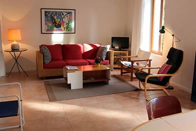 Salon moderne avec canapé rouge et fauteuils design cosy Salon chaleureux avec canapé rouge, fauteuil design noir, table basse en bois et tapis gris sur sol carrelé.