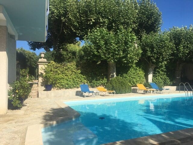 Piscine Extérieure et Jardin pour une Détente Solaire Piscine extérieure avec eau bleue cristalline, transats colorés et jardin luxuriant sous un ciel bleu dégagé.
